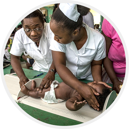 Two healthcare workers in Haiti performing a checkup on a baby